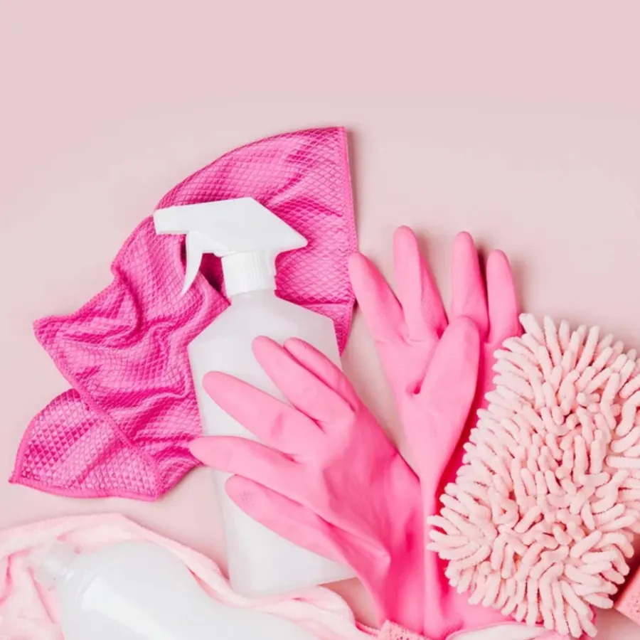 White spray bottle on a pink microfiber cloth with pink gloves and a dusting mitt