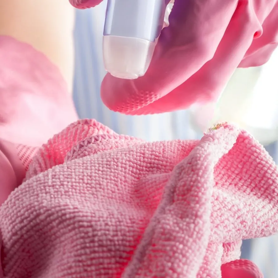 Close up of a spray bottle misting a pink microfiber cloth
